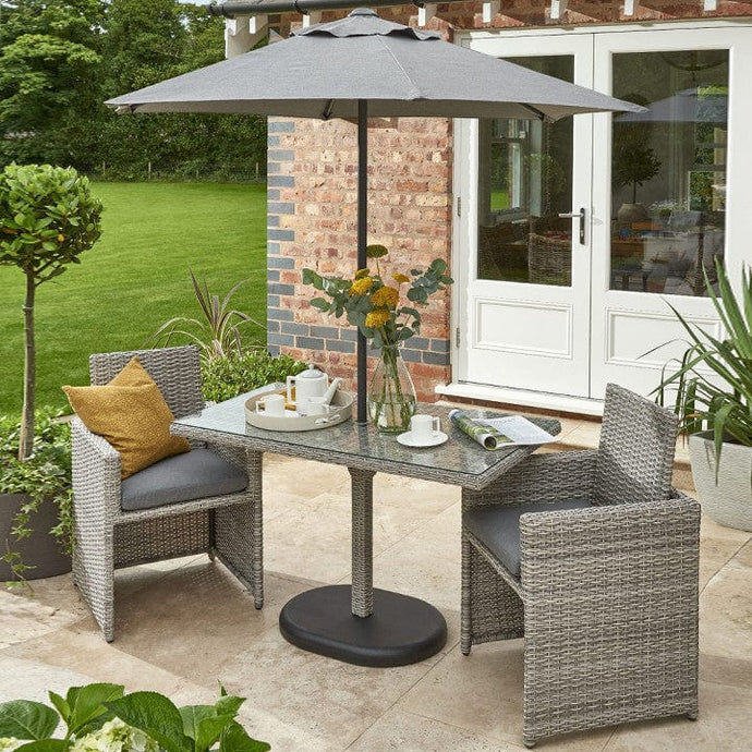 grey bistro set with dark grey cushions, a glass topped rectangular table and 1 parasol