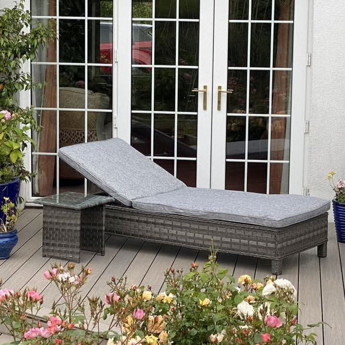 dark grey lounger with grey cushions and a small glass topped square side table