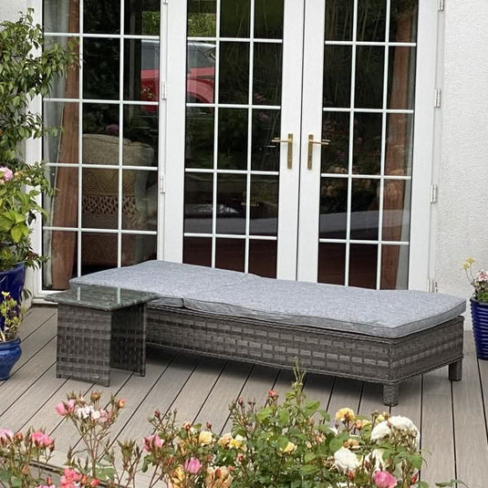 dark grey lounger with grey cushions and a small glass topped square side table