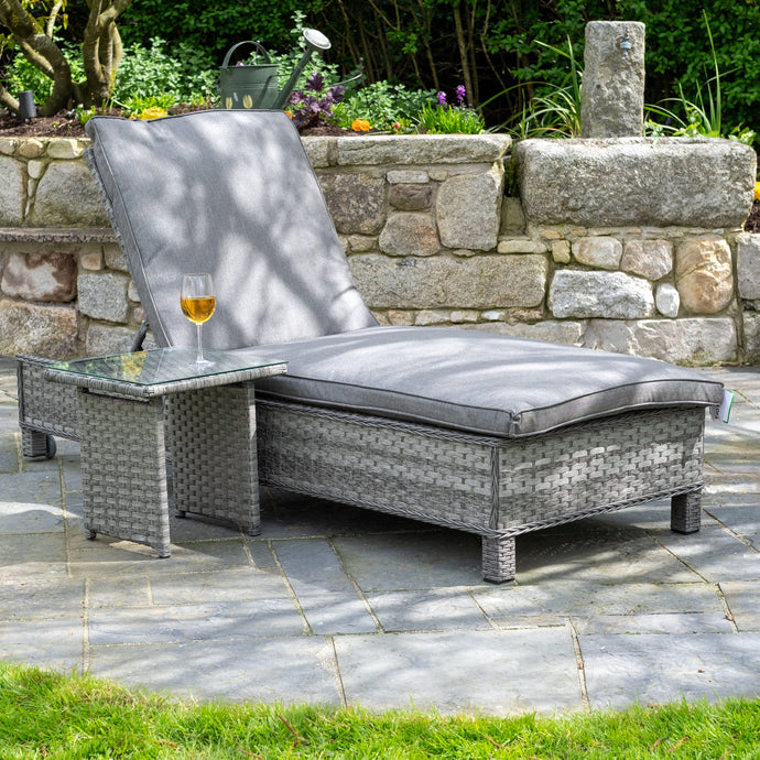 grey sun lounger with cushions and a small rectangular table