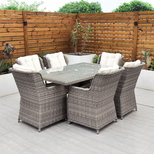 grey 6 seat set with cream cushions and a glass topped rectangular table with a hole for a parasol centrally situated within the table