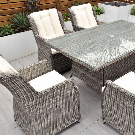 grey 6 seat set with cream cushions and a glass topped rectangular table with a hole for a parasol centrally situated within the table