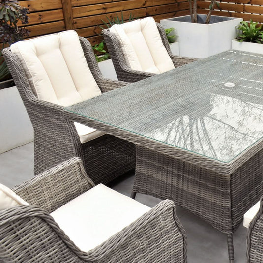 grey 6 seat set with cream cushions and a glass topped rectangular table with a hole for a parasol centrally situated within the table